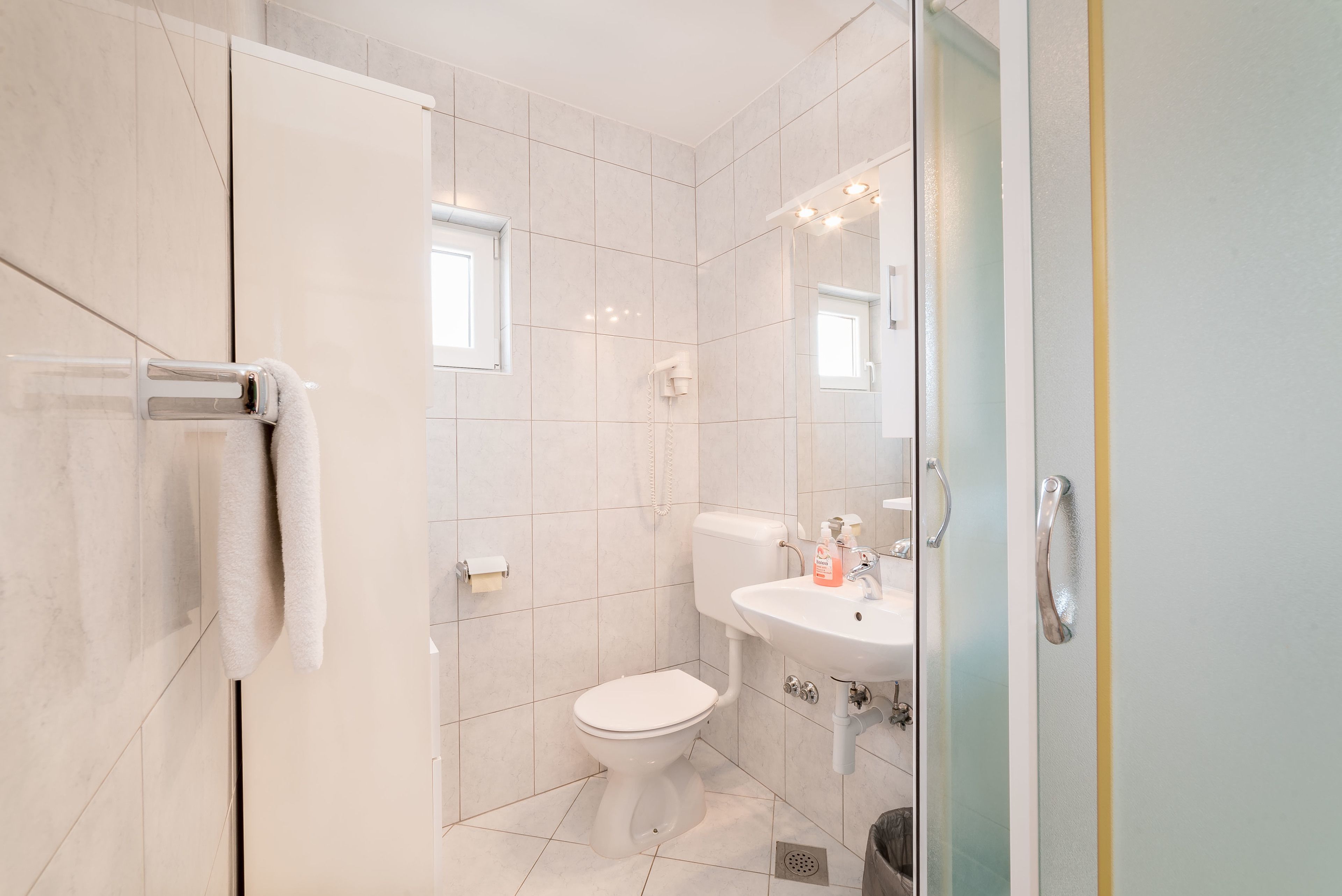 A modern bathroom with a toilet, sink, and glass shower enclosure.