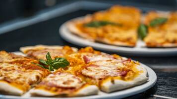 A plate of pizza with cheese and ham, garnished with basil leaves.