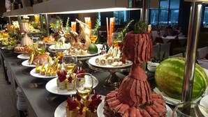 Un bufé con diversos platos, entre ellos carnes, quesos y frutas.