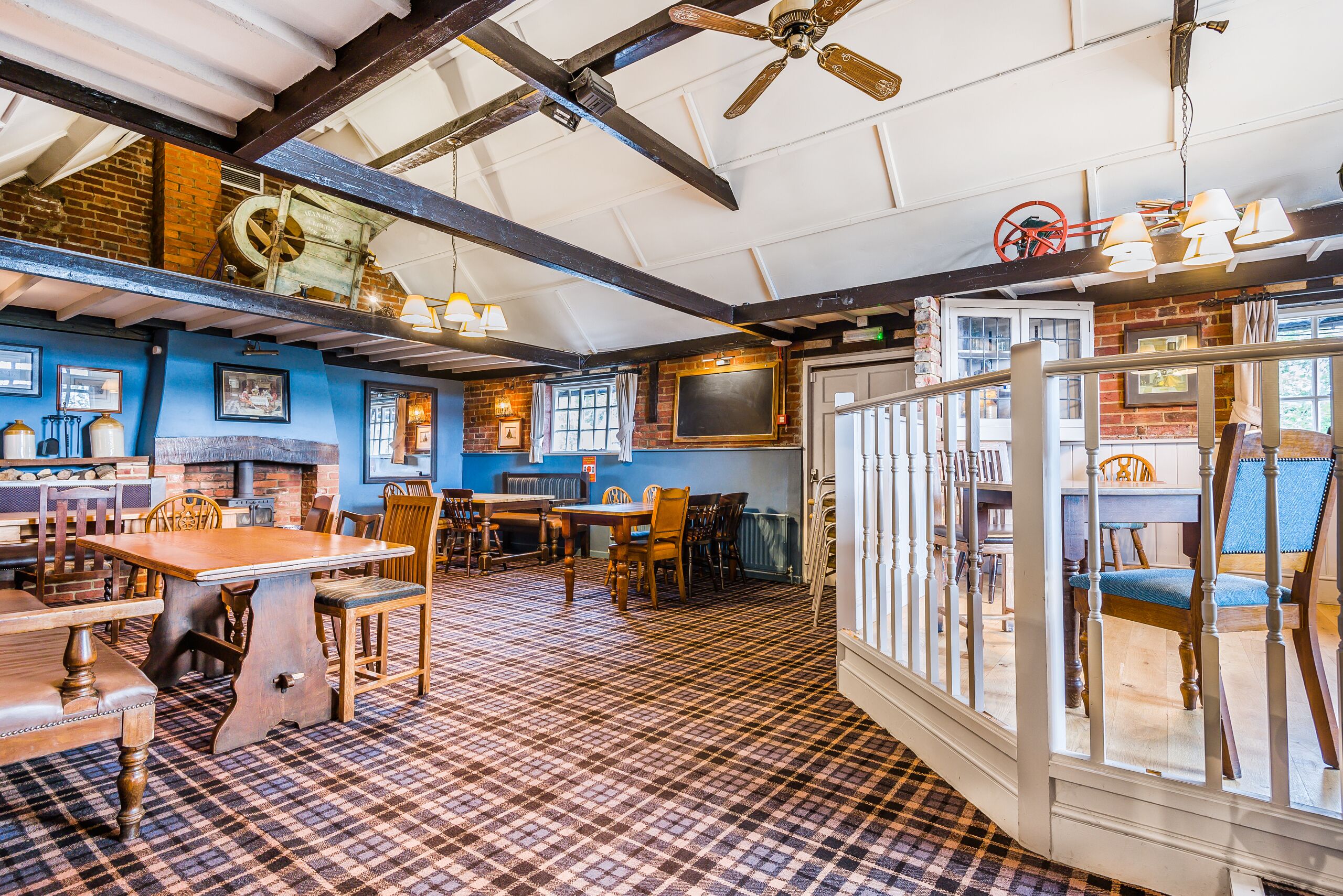 Un restaurant avec un sol à carreaux, des tables et des chaises en bois, un mur en briques et un ventilateur de plafond.