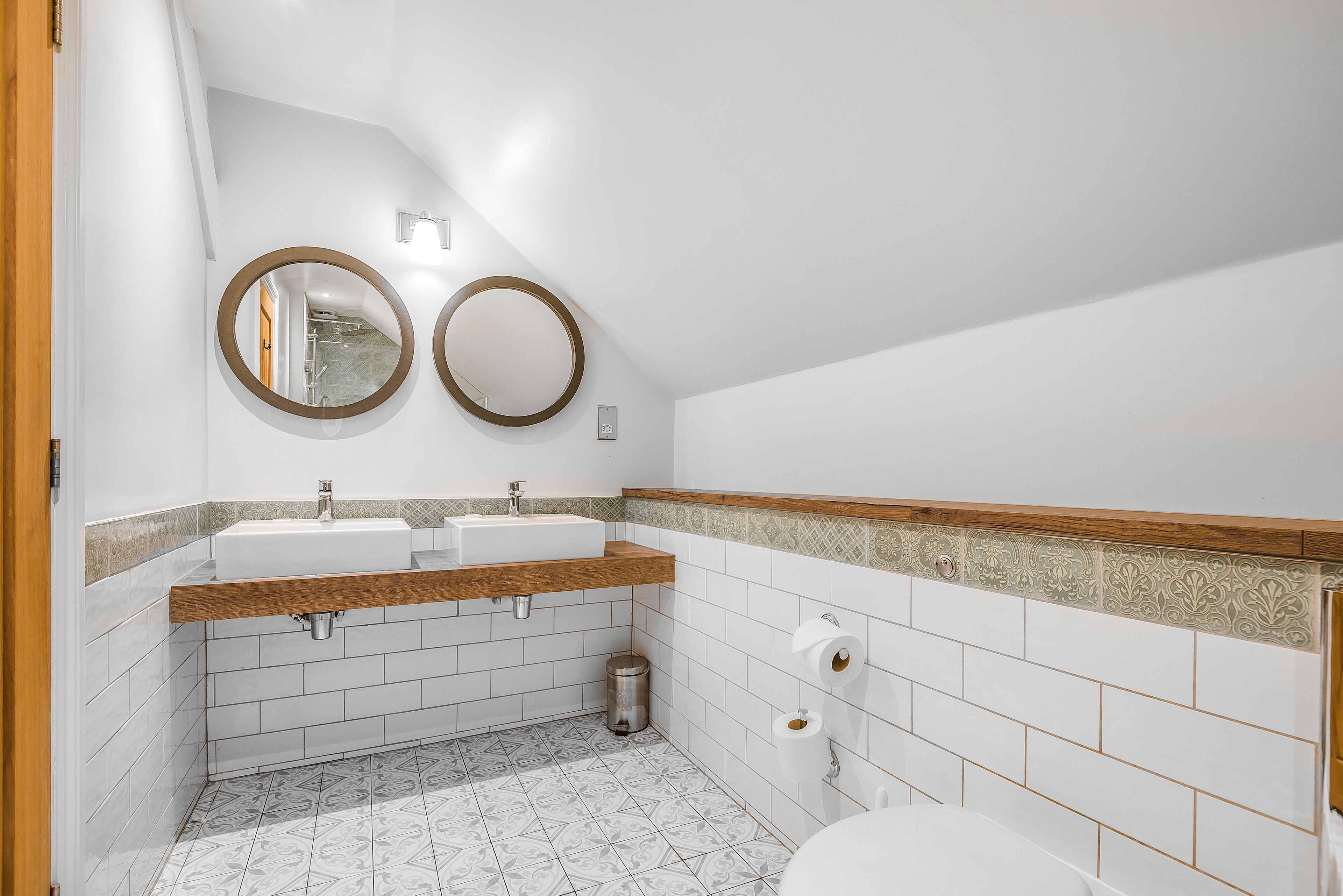 Une salle de bain avec deux lavabos, des toilettes et une poubelle.