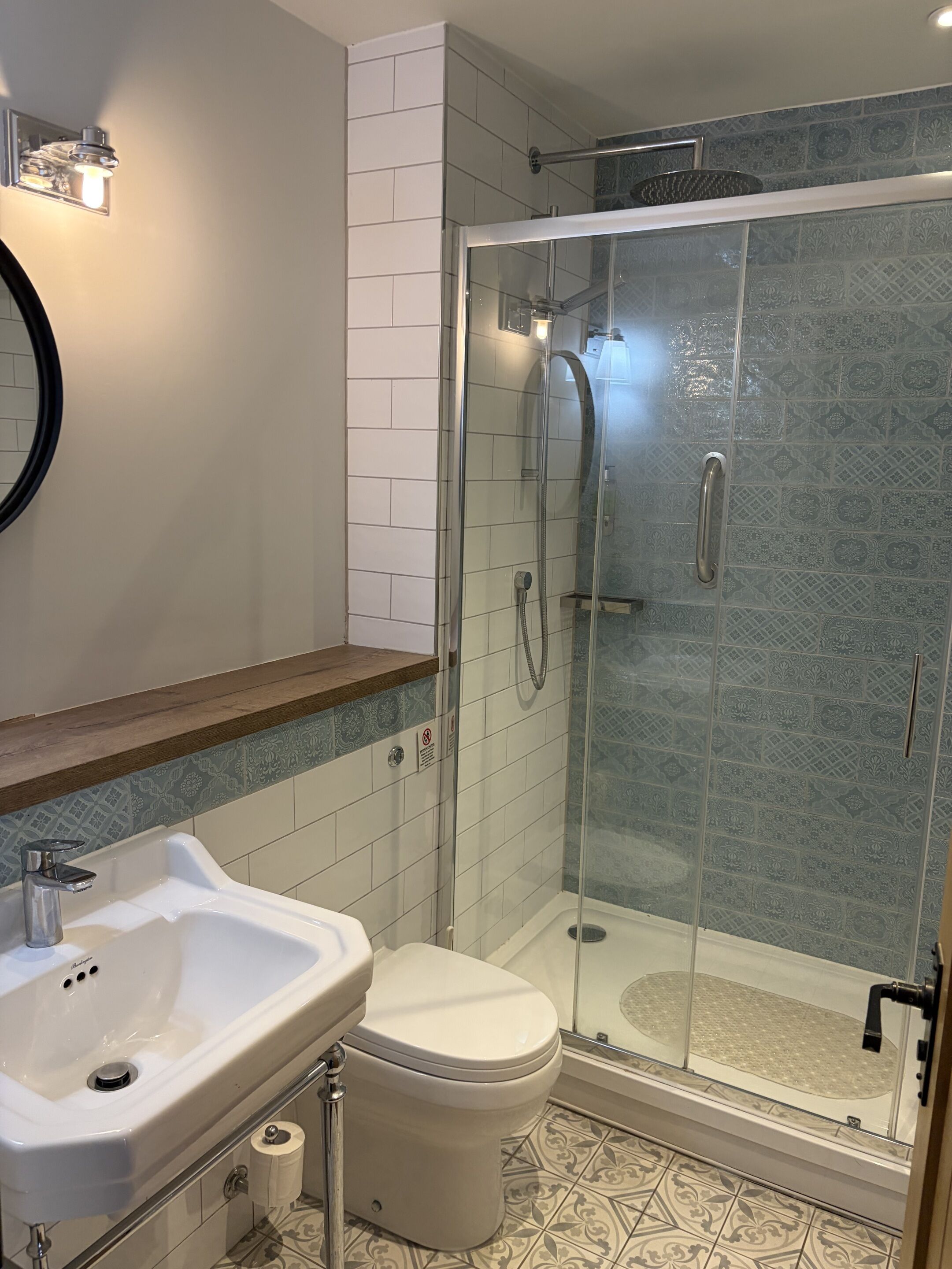 Un baño moderno con cabina de ducha de vidrio, lavabo blanco y un inodoro.