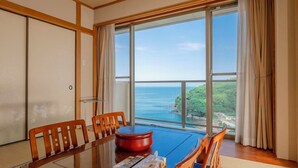 A spacious room with a large wooden dining table, comfortable chairs, and a view of the sea. - Manazuru Marin (Manazuru)