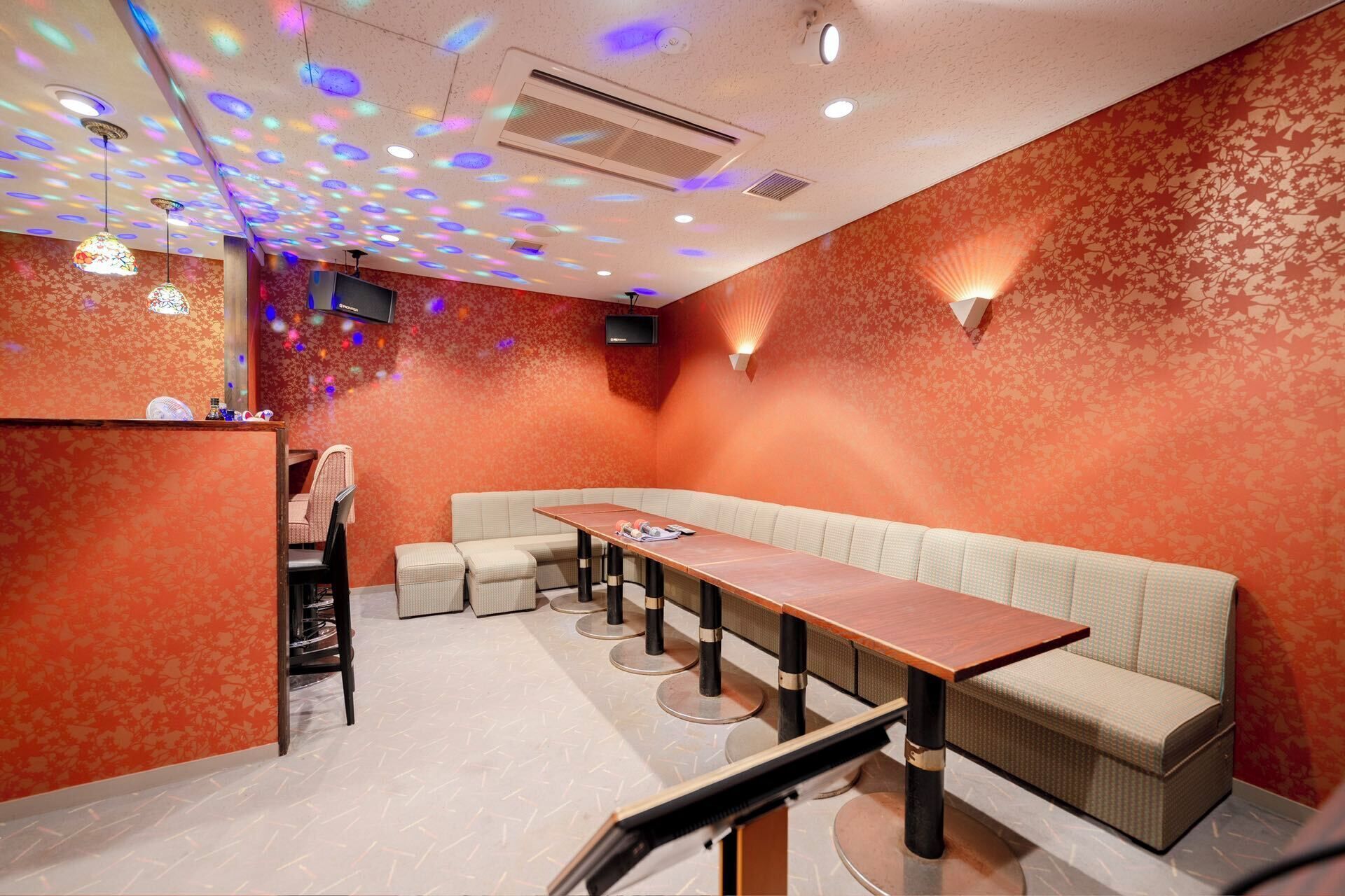 Un restaurante con una larga mesa de madera, asientos acolchados y un muro con diseño.