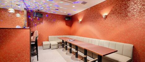 Un restaurante con una larga mesa de madera, asientos acolchados y un muro con diseño.