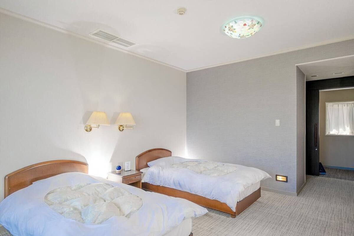 Quarto de hotel com duas camas, uma mesa pequena e uma mesa de cabeceira.