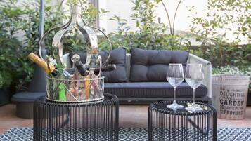 Eine Terrassenfläche mit einem schwarzen Metalltisch und einem Glasflaschenhalter, der Champagnerflaschen und Gläser enthält.