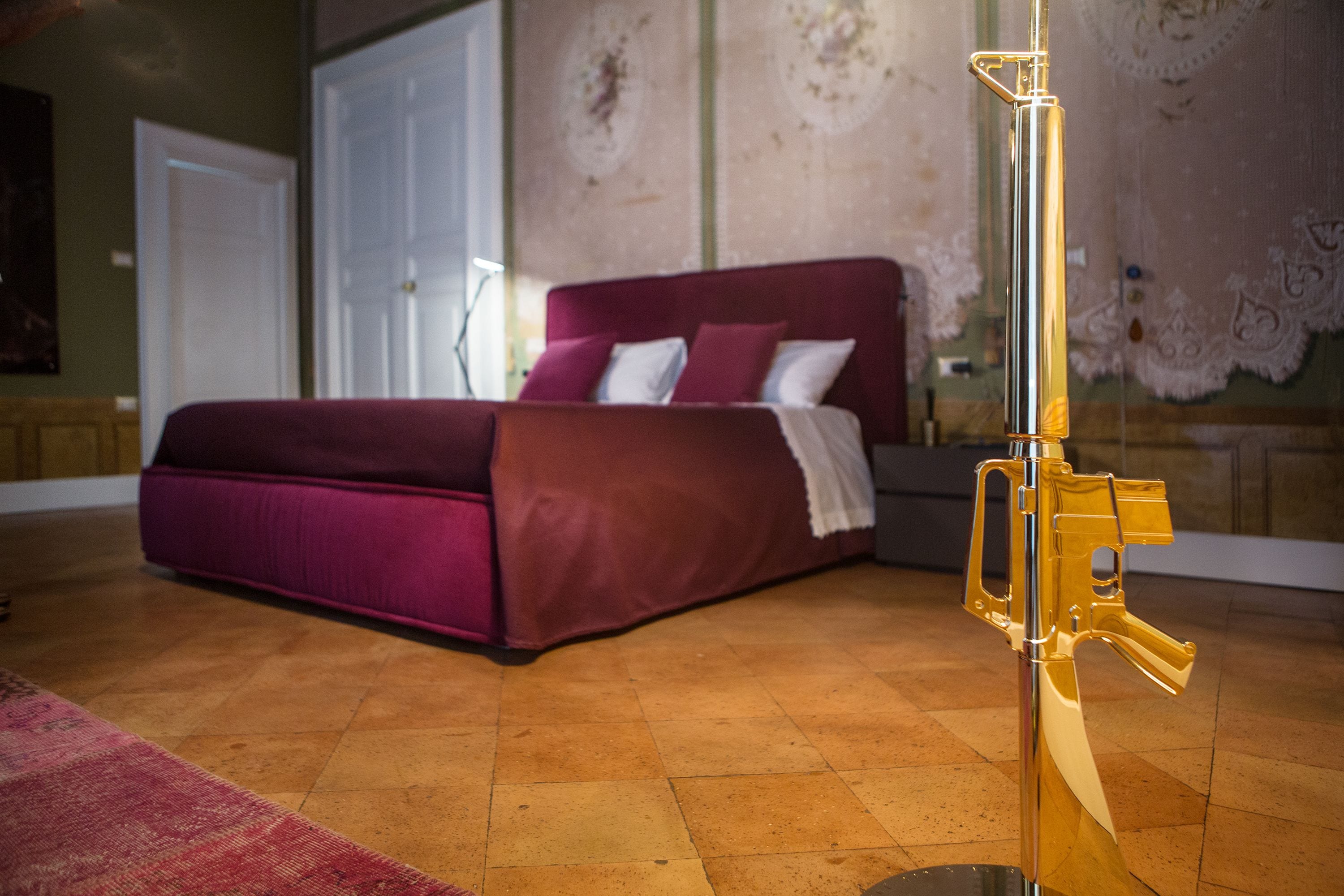 A bedroom with a large bed, a red headboard, and a decorative wall.