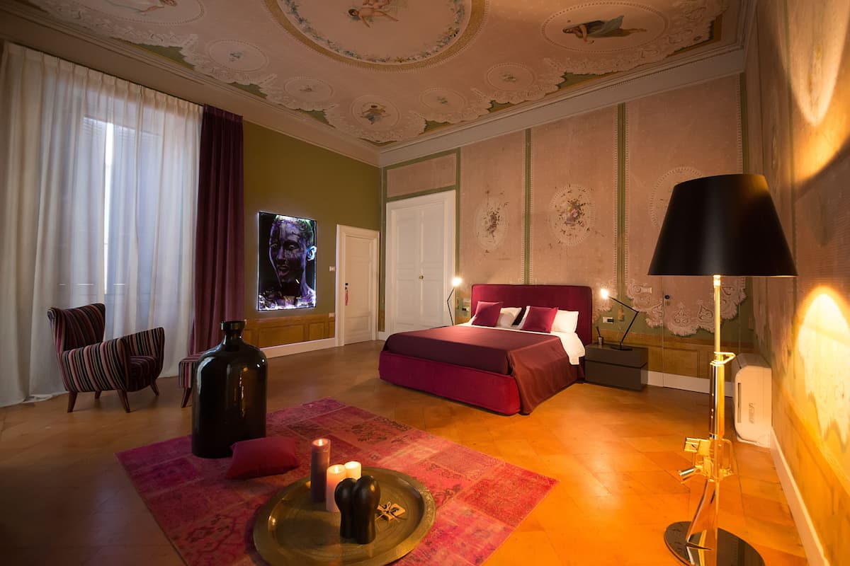 A bedroom with a bed, a chair, a lamp, and a TV.