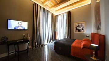 Una habitación de hotel con cama, escritorio, televisor y un cuadro en la pared.