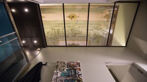 Un baño con cabina de ducha de vidrio, un perchero y un panel decorativo en la pared.