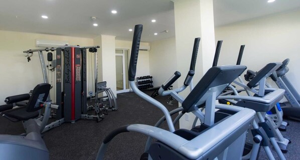 A gym with various exercise equipment including treadmills, weight machines, and dumbbells.