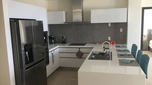 Una cocina moderna con refrigerador integrado, cafetera y lavamanos.