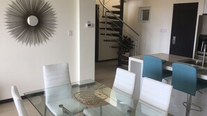 Una cocina moderna con una mesa de vidrio, sillas blancas y una escalera en espiral.