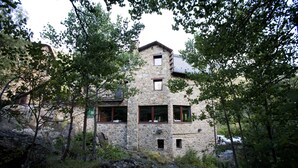 A stone building with multiple windows, surrounded by trees and rocks. - Hotel & Spa Niunit (El Serrat)