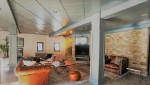A modern living room with a fireplace, leather sofas, and a stone accent wall. - Hotel & Spa Niunit (El Serrat)