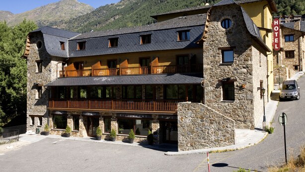 A stone building with a wooden balcony and a sign reading "HOTEL". - Hotel & Spa Niunit (El Serrat)