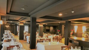 A restaurant with multiple tables set for dining, featuring white tablecloths and neatly arranged cutlery. - Hotel & Spa Niunit (El Serrat)