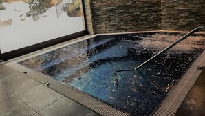 A hot tub with a stone wall backdrop and a projection screen displaying a snowy scene. - Hotel & Spa Niunit (El Serrat)