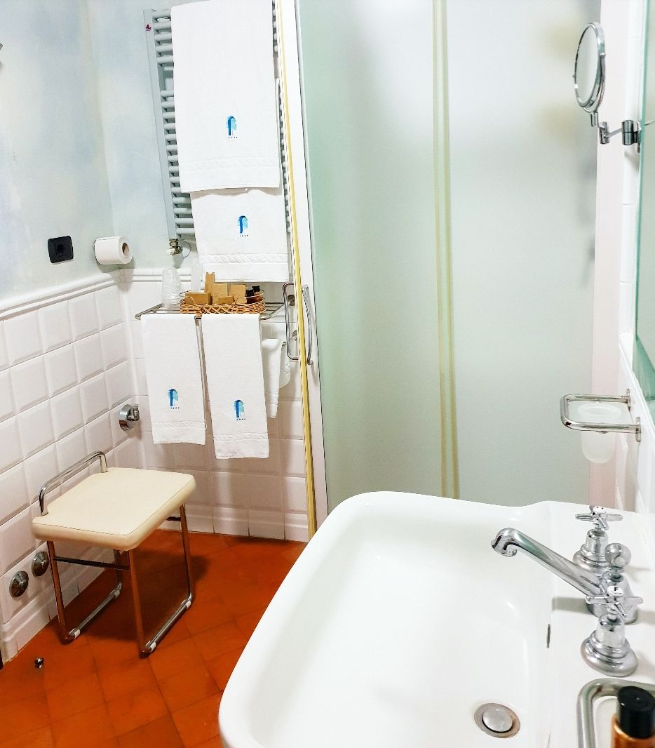 A bathroom with a white sink, a mirror, a towel rack, and a shower area.