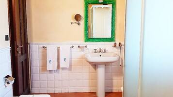 Et badeværelse med toilet, bidet, vask og spejl.