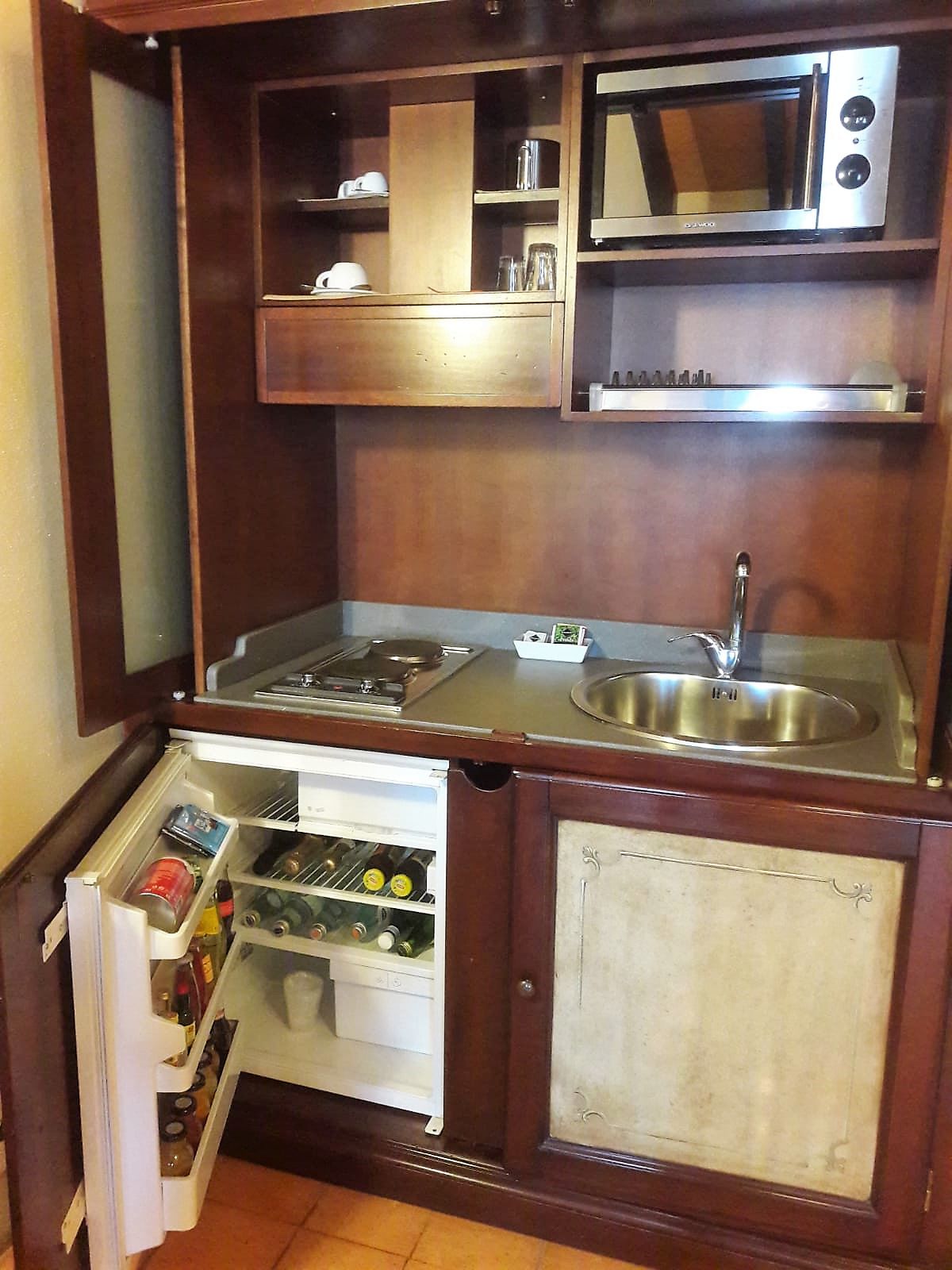 Eine kleine Küchenzeile mit Mikrowelle, Spüle und kleinem Kühlschrank.