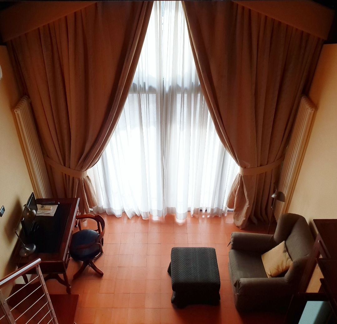 Ein Zimmer mit Schreibtisch, Stuhl, Hocker und Sofa.