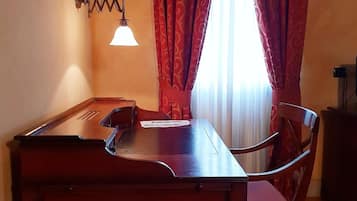 A dining area with a wooden table and chairs, a wall-mounted light fixture, and red patterned curtains.