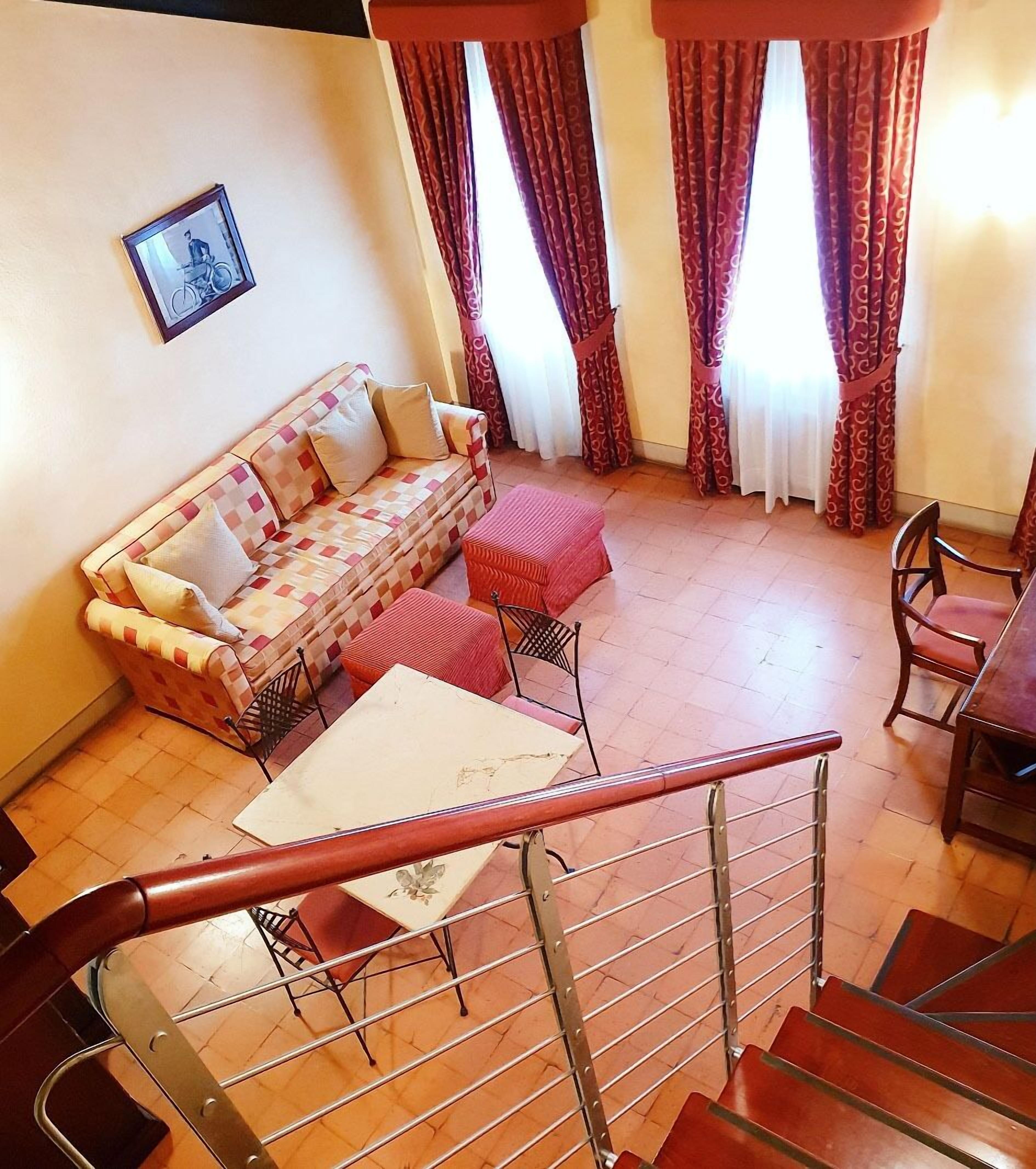 A living room with a sofa, ottoman, and a dining area with chairs and a table.