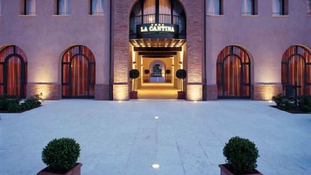 Een hotelentree met een centrale boog, twee symmetrische vleugels en een bord waarop 