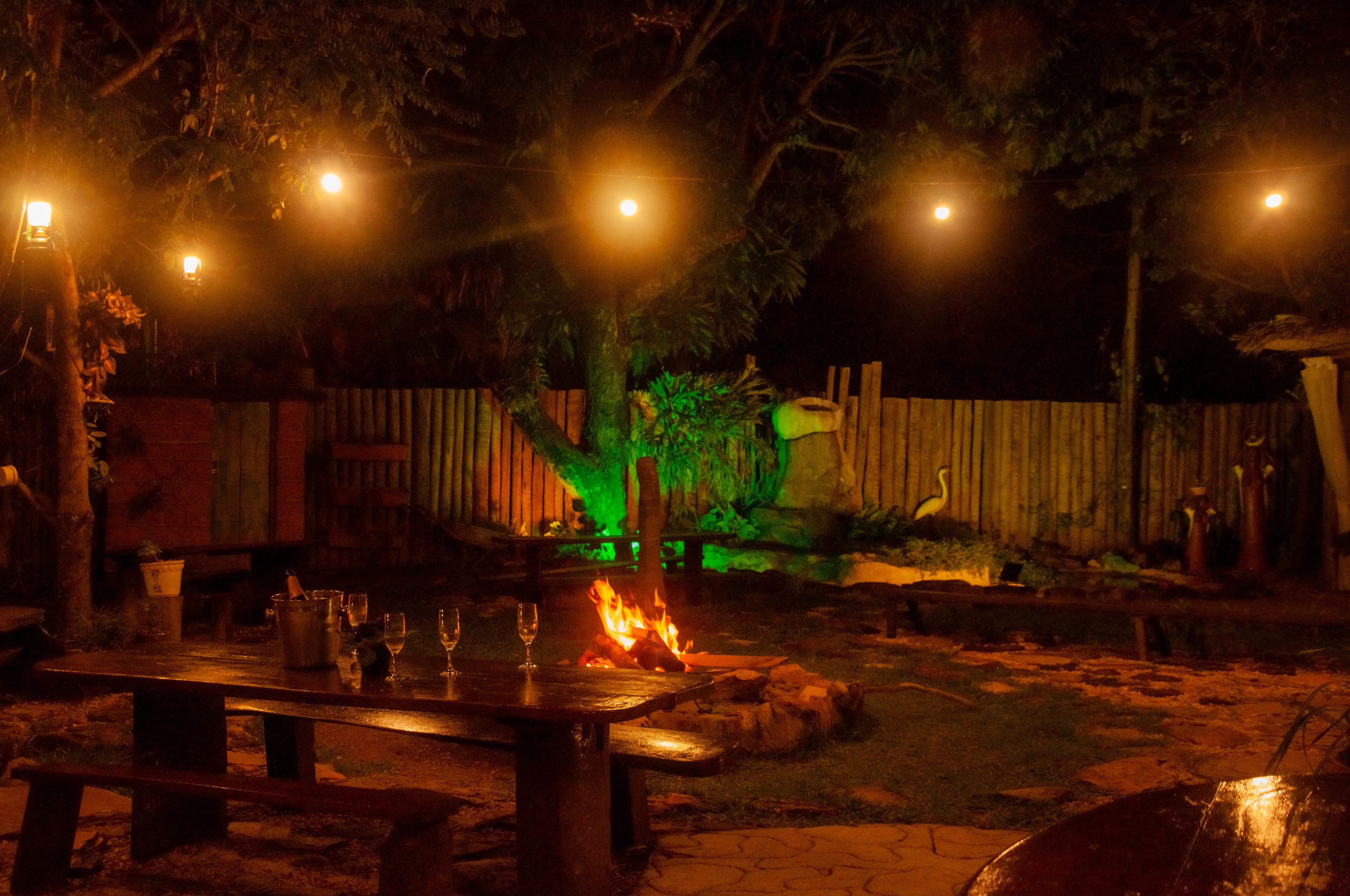 An outdoor dining area with a fire pit, wooden table, and benches.