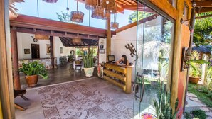 A spacious lobby with a wooden reception desk, patterned floor, and hanging wicker chandeliers. - Pousada Caminho das Cachoeiras (Alto Paraíso de Goiás)