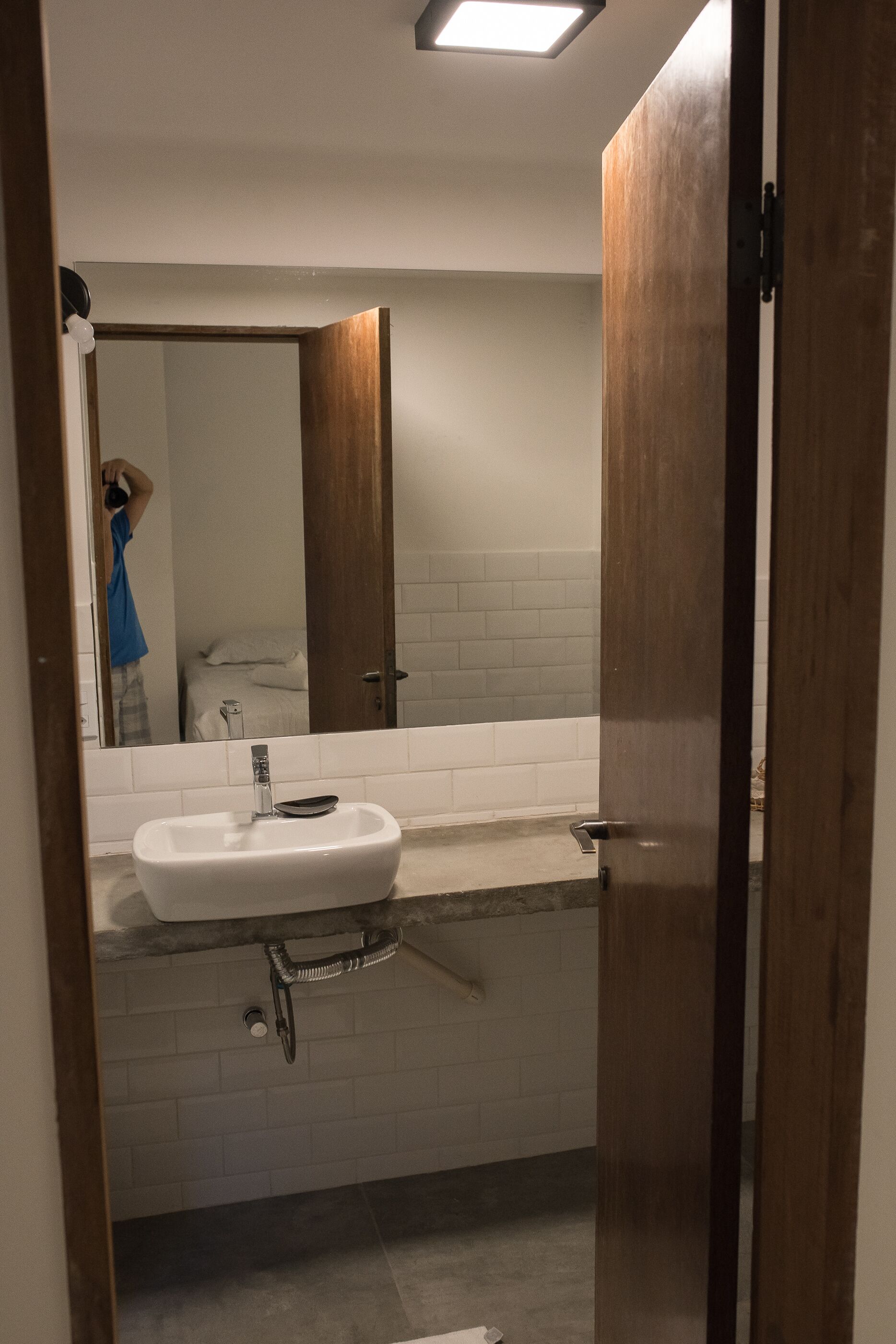 A bathroom with a white sink, a mirror, and a wooden door.