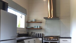 Eine moderne Küche mit weißen Schränken, einem Edelstahl-Kühlschrank, einem eingebauten Backofen und einer Dunstabzugshaube.