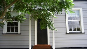 Ein Haus mit Veranda, einer Holztreppe und zwei Fenstern.