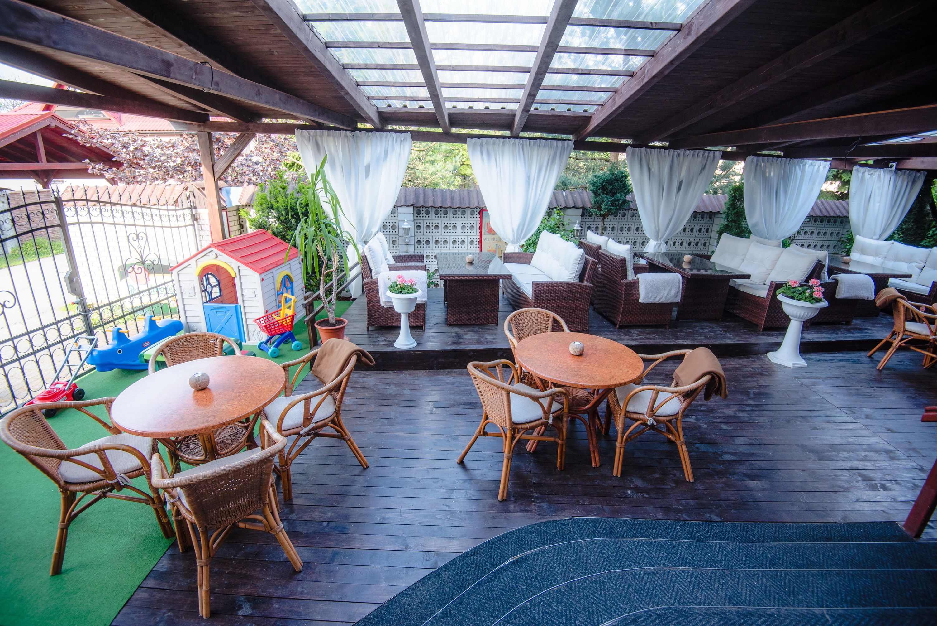 An outdoor patio area with wicker furniture, a small playhouse, and a covered seating area.