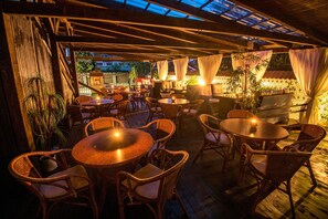 An outdoor patio area with wicker furniture and tables, featuring a wooden ceiling and natural light from the sky. - Penzión PANDA (Turcianske Teplice)