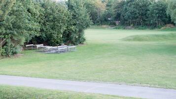 A golf course with a clear path, benches, and dense trees.