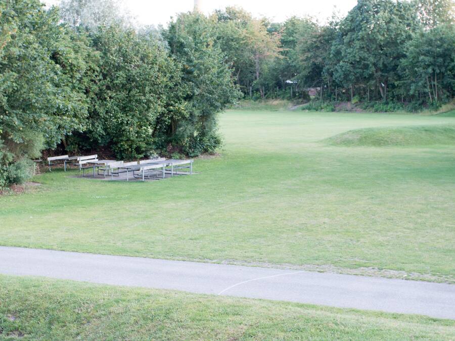 A golf course with a clear path, benches, and dense trees.