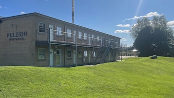Un bâtiment en briques portant l’inscription « Pulzion Sports Hotel », avec de nombreuses fenêtres et un escalier menant à un balcon.