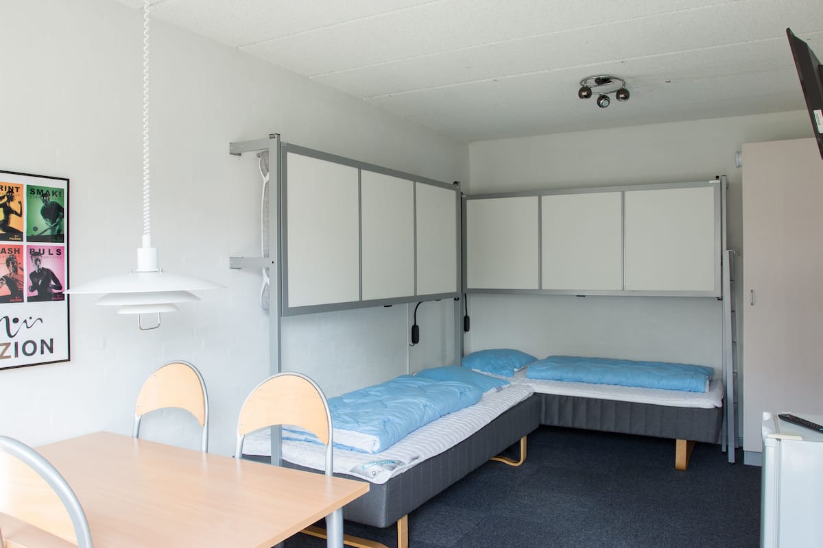 A compact room with two single beds, a small table, and chairs.