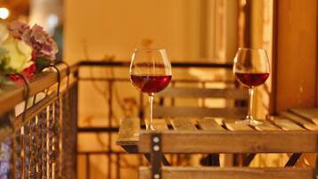 Dos copas de vino tinto sobre un banco de madera con barandilla metálica.