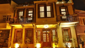 A two-story building with a red carpet entrance, potted plants, and a balcony with railing. - Mimoza Butik Otel Buyukada (Adalar)