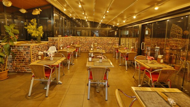 A restaurant with brick walls, wooden tables, and wicker chairs. - Mimoza Butik Otel Buyukada (Adalar)