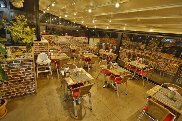 A restaurant with brick walls, wooden tables, and metal chairs. - Mimoza Butik Otel Buyukada (Adalar)