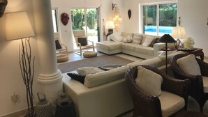 A spacious living room with a large sectional sofa, a fireplace, and a view of a swimming pool. - Luxury Villa With Private Pool (Albufeira)