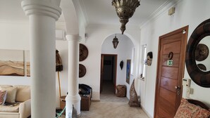 A hallway with white columns, a wooden door, and a bench with patterned cushions. - Luxury Villa With Private Pool (Albufeira)
