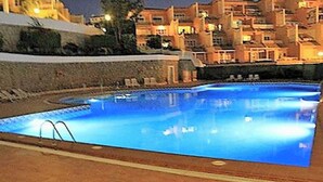 A swimming pool with a clear blue water surface, surrounded by a tiled deck and a low stone wall. - Luxurious apartment with all comforts - 3 swimming pools - sunshine all day (adeje)
