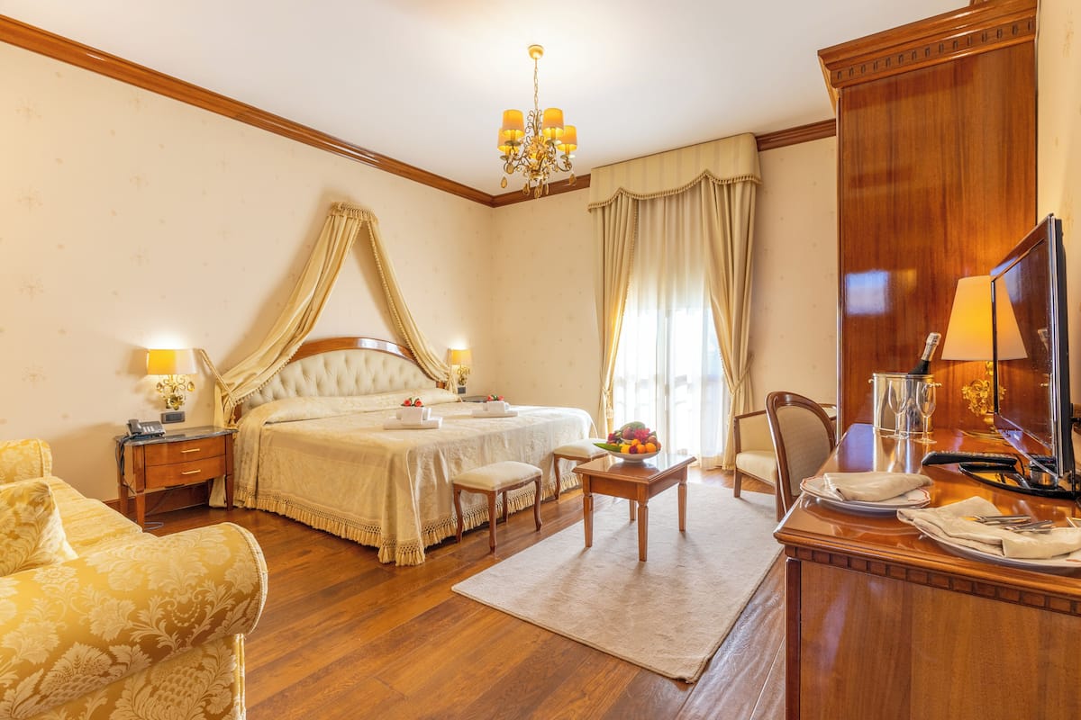 Une chambre d’hôtel comprenant un lit, une table de chevet, une chaise, un bureau et un téléviseur.