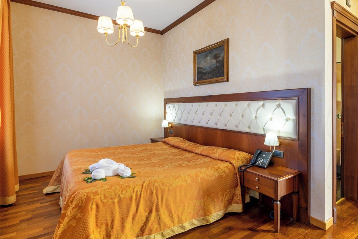 Une chambre d’hôtel avec un grand lit, un téléphone sur la table de chevet et une petite table de nuit.